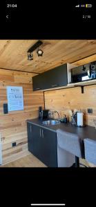een keuken met een wastafel en een houten muur bij La Tiny house in Ardres