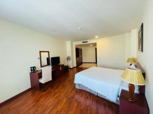 a hotel room with a bed and a table and a lamp at The Western Hill Hotel in Da Lat