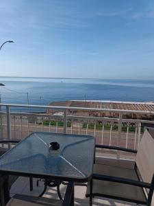 a glass table on a balcony with a view of the beach at Marina's Boutique in Alexandroupoli