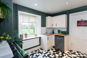 a kitchen with white cabinets and a checkered floor at Estate Lodge Sleeps 5 on The Jurassic Coast Devon in Sidbury