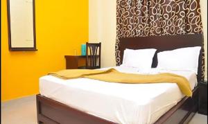 a bedroom with a bed with yellow walls at FabExpress Century Gardens in Bangalore