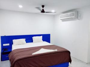 een slaapkamer met een bed met een blauw hoofdeinde bij HOTEL NEW RATNAKAR in Daman