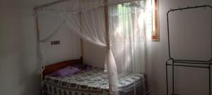 1 dormitorio con cama con dosel y ventana en Wijesingha Holiday Home, en Weligama