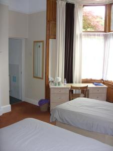 a bedroom with two beds and a desk and a window at Meadowbank in Ambleside