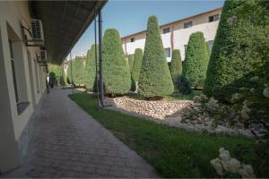a row of trees and bushes next to a building at Rohat Mirobod in Tashkent