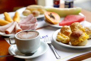 a table with plates of food and a cup of coffee at Dexter Hotel - Volta Redonda in Volta Redonda +43 photos