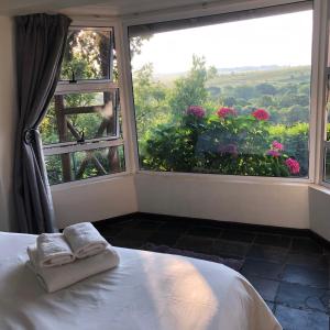 a bedroom with a bed and a large window with flowers at Hills and Dales Accommodation in Lanseria