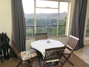 mesa y sillas en una habitación con ventana grande en Hills and Dales Accommodation en Lanseria