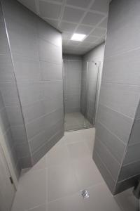 uma casa de banho com uma cabina de duche ao nível do chão com azulejos brancos em CEVAHIR SKY CITY Skopje JK Apartments em Skopje