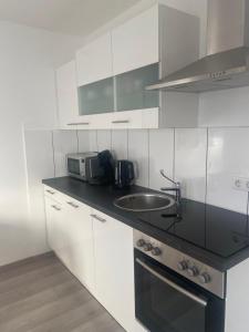 a white kitchen with a sink and a microwave at Gemütliches Zuhause in 1A Lage in Herne