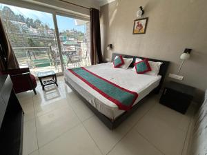 um quarto com uma cama e uma grande janela em HOTEL JP REGENCY em Nainital