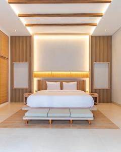 a bedroom with a large white bed and a bench at The Clara Ville in Canggu