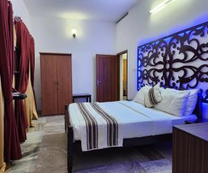 een slaapkamer met een groot bed met een blauw hoofdeinde bij Bharatham Heritage Inn in Kannur