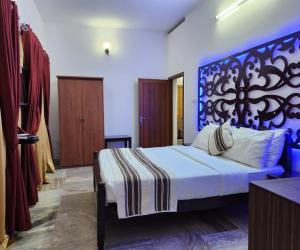 une chambre avec un grand lit avec une tête de lit bleue dans l'établissement Bharatham Heritage Inn, à Kannur