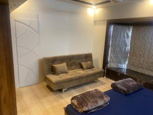 uma sala de estar com um sofá e dois repousa-pés em Bandra’s Prime luxurious 2 BHK em Mumbai