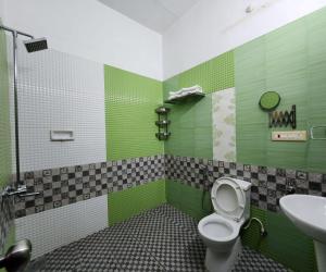 een groene badkamer met een toilet en een wastafel bij Bharatham Heritage Inn in Kannur