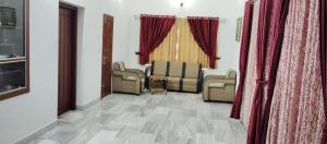un salon avec des canapés et des rideaux rouges dans l'établissement Bharatham Heritage Inn, à Kannur 29 autres photos