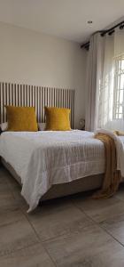 a bedroom with a large bed with yellow pillows at Adante @ Midrand in Midrand