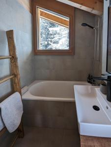 La salle de bains est pourvue d'une baignoire, d'un lavabo et d'une fenêtre. dans l'établissement Chalet Adler, à Saas-Fee