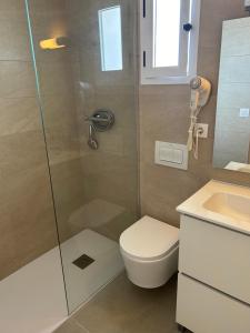 a bathroom with a shower and a toilet and a sink at Hostal Cala Moli in Cala Tarida