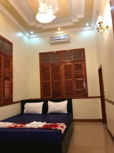 a bedroom with a bed and wooden shuttered windows at Leng Seng Na Hotel in Battambang