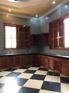 a large kitchen with wooden cabinets and a checkered floor at Leng Seng Na Hotel in Battambang