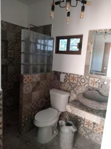 La salle de bains est pourvue de toilettes, d'un lavabo et d'un miroir. dans l'établissement Casa orquídea, à Oacalco