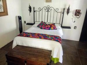- une chambre avec un lit doté d'une couverture blanche et d'oreillers colorés dans l'établissement Casa orquídea, à Oacalco