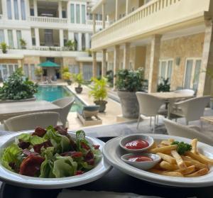 a table with two plates of food and french fries at Bali Court Hotel & Apartment in Legian