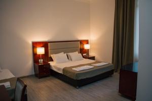 a bedroom with a bed with two night stands and two lamps at Zhebota garden Tianeti in Zhebota