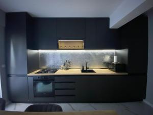 a black kitchen with a sink and a stove at AIR Studio & Garden in Otopeni