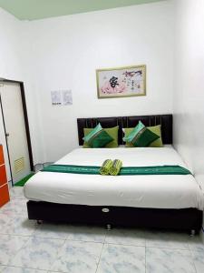 een slaapkamer met een groot bed met groene kussens bij Greenhouse homestay betong in Betong
