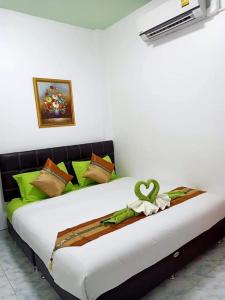 een bed in een kamer met groene en bruine kussens bij Greenhouse homestay betong in Betong