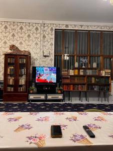 sala de estar con TV y mesa en el centro en СОФЬЯ ГОСТЕВОЙ ДОМ, en Bukhara