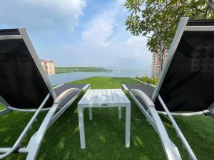 twee stoelen en een witte tafel op het gras bij Stylish Urban Suites Georgetown Sea View in Jelutong