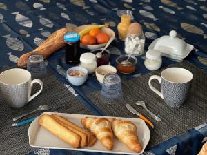 una mesa con un plato de cruasanes y otros productos para el desayuno en Le Caux ´Sy en Senneville-sur-Fécamp