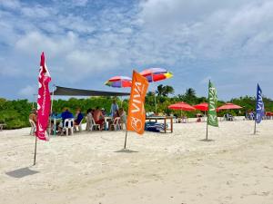 a group of flags on a beach with people sitting under umbrellas at VIVA Beach Maldives in Hangnaameedhoo