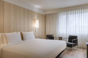 una habitación de hotel con una gran cama blanca y una mesa en AC Hotel Córdoba by Marriott, en Córdoba