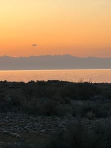 a sunset over the water with mountains in the background at Guest house and Yurt camp "Ailuu" in Tong