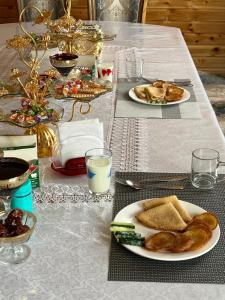 a table with plates of food and glasses of milk at Guest house and Yurt camp "Ailuu" in Tong