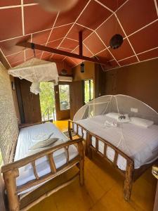 two beds are in a room with a ceiling at Yala Eco Tree House in Tissamaharama