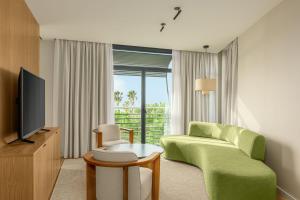 uma sala de estar com um sofá verde e uma televisão em AC Hotel Gava Mar em Gavà