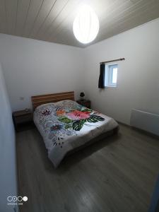 um quarto com uma cama com um edredão floral em Logement au coeur de l'Auvergne em Lorlanges