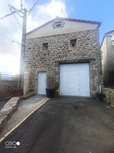 um edifício de pedra com duas portas de garagem brancas em Logement au coeur de l'Auvergne em Lorlanges