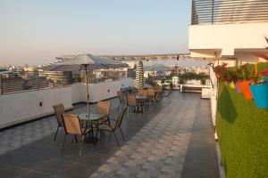 einen Balkon mit Tischen, Stühlen und einem Sonnenschirm in der Unterkunft Posh Garden Inn Artemis Hospital Road Gurgaon in Gurgaon