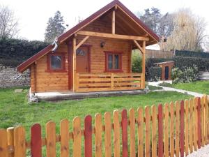a wooden cabin with a fence in a yard at Le petit chalet jurassien in Jouhe