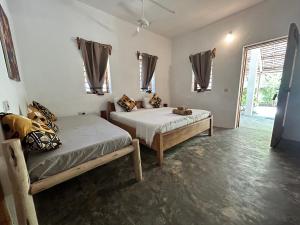 a bedroom with two beds and a window at BONDENI BEACH HOUSE in Jambiani