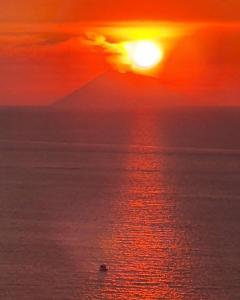 a sunset over the ocean with a boat in the water at BLOOM in Tropea
