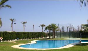 einen Pool in einem Park mit Palmen in der Unterkunft Dúplex en primera línea Playa Faro in Garrucha