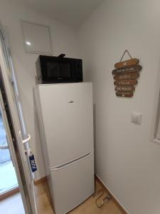 einen weißen Kühlschrank mit einer Mikrowelle darüber in der Unterkunft Studio neuf des amandines in Pont-Sainte-Maxence